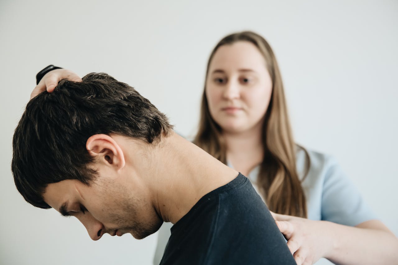 A physiotherapist helps a patient with neck exercises in a clinic setting.