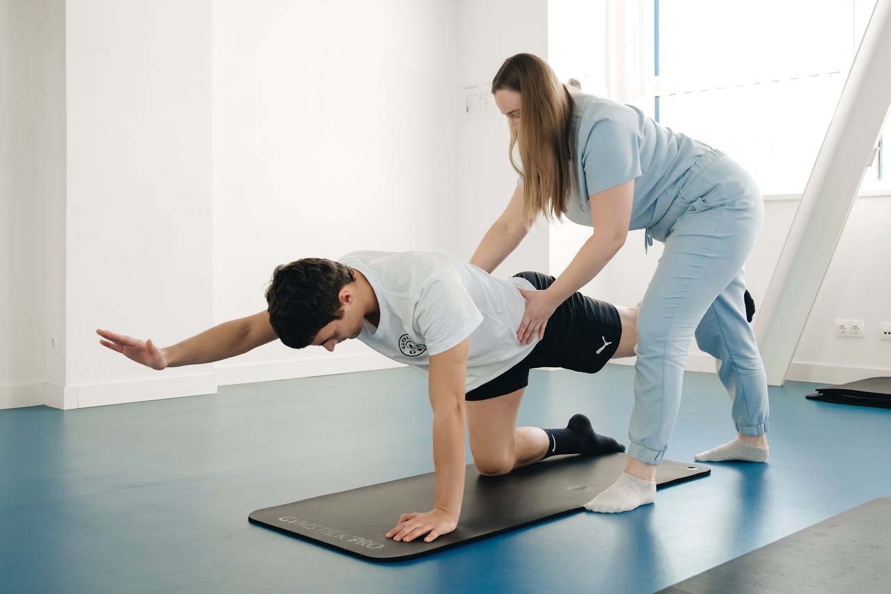 A physiotherapist guides a patients exercise on a mat in a Vilnius gym.